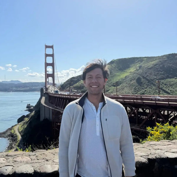 Person standing in front of the Golden Gate Bridge with a clear blue sky.